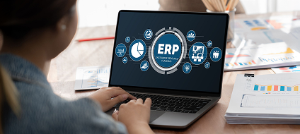 An ERP dashboard open on a laptop beside business paperwork